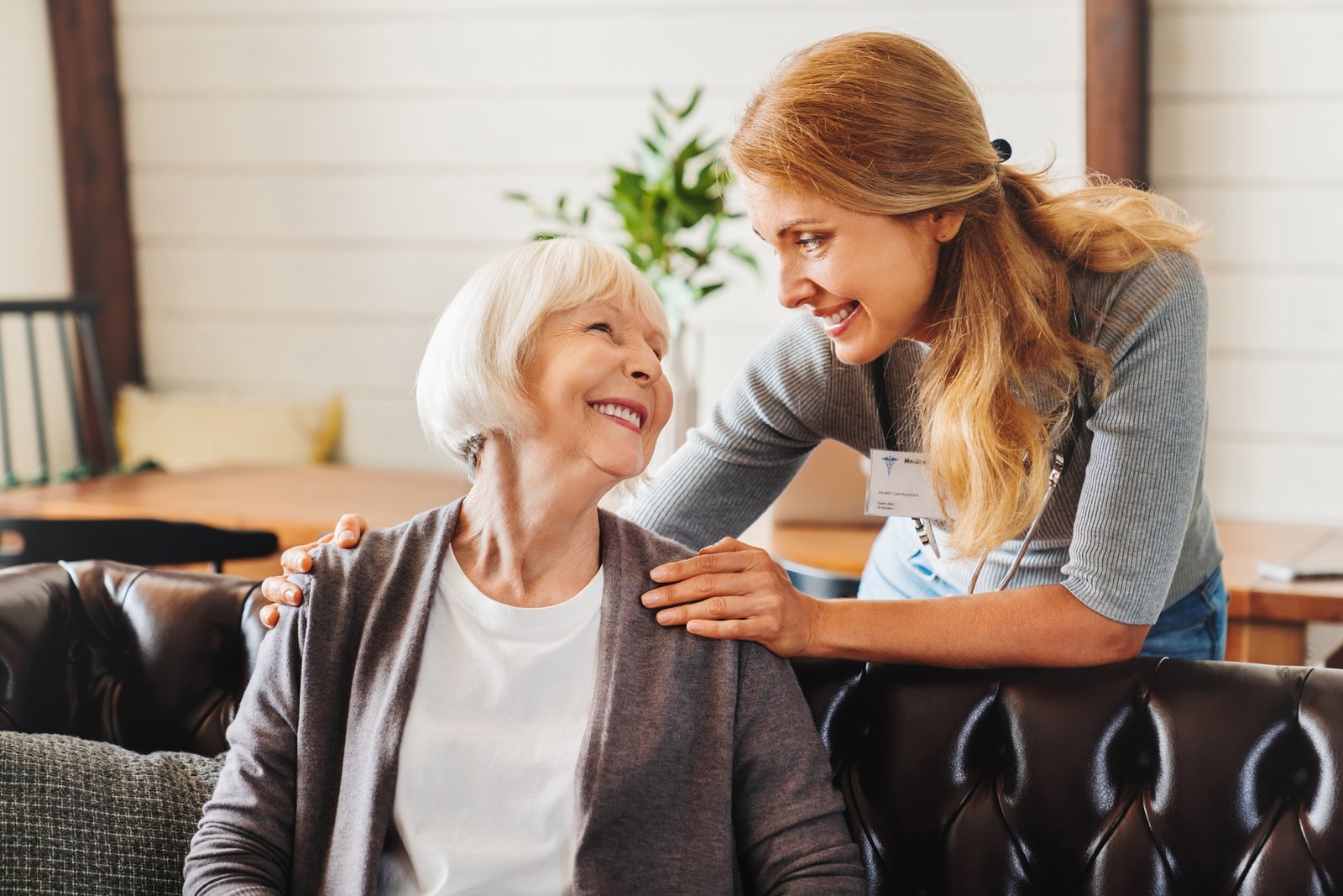 Middle aged nurse taking care of old woman indoors