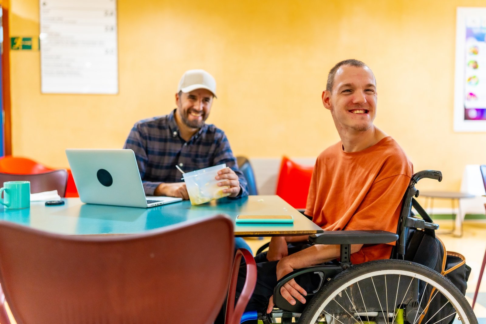 Disabled man and coworker eating together in the dinning room